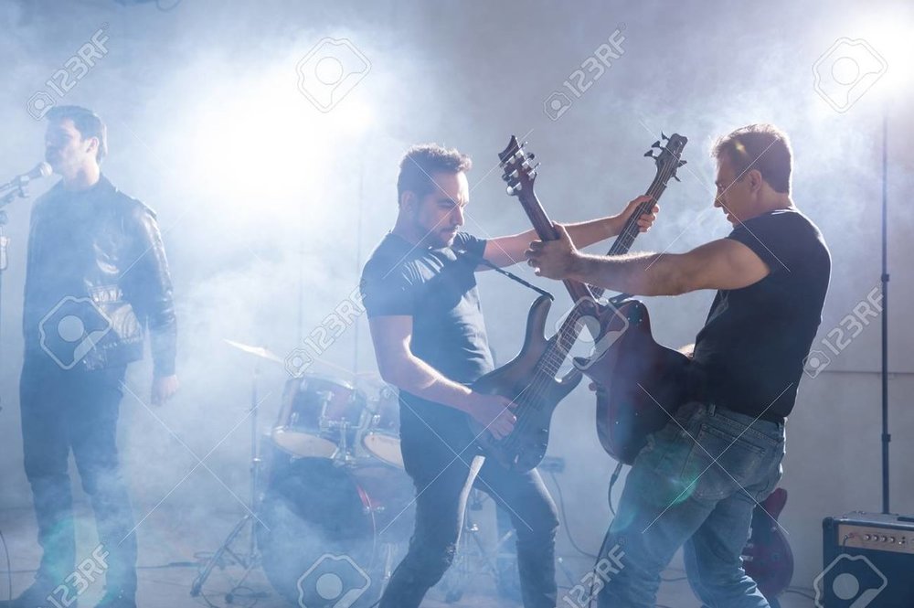 102839474-two-young-man-playing-guitars-on-stage-with-lead-singer-at-the-back-at-a-live-concert.jpg